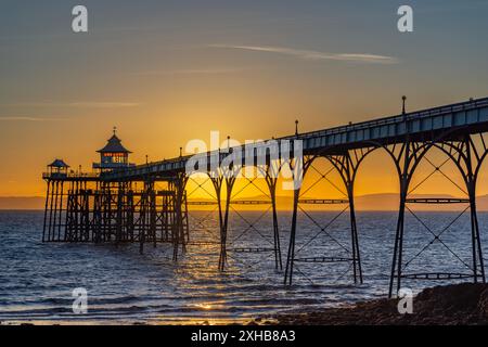 Clevedon Pier bei Sonnenuntergang an einem hellen Abend mit goldenem Glanz im Hintergrund Stockfoto