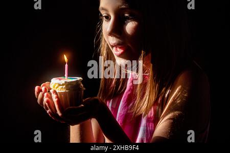 Kerzen blasen Geburtstagsparty kleines glückliches Mädchen. Kindergeburtstag. Kleines süßes Mädchen, das sich wünscht, Kerzen auf Kuchen zu ihrem Geburtstag aufzupusten Stockfoto