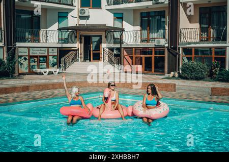 Drei Frauen sitzen auf aufblasbaren Wagen in einem Pool. Die Szene ist unbeschwert und lustig. Stockfoto