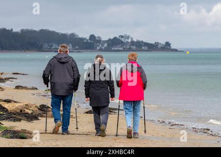 Drei Freunde mittleren Alters, die gemeinsam am Strand spazieren gehen Stockfoto
