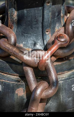 Große, rostige Ankerkette eines Schiffes um eine große Lasche oder einen Poller. Ausrüstung für See- und Seeschiffe. Stockfoto