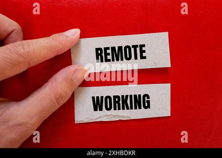 Meldung für die Fernbearbeitung auf Papierstücken mit rotem Hintergrund. Konzeptionelles Symbol für Remote Working. Kopierbereich. Stockfoto