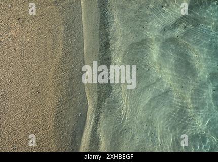 Ein Blick von oben auf das klare, flache Meereswasser mit Sonnenlichtreflexionen an einem Sandstrand auf der Insel Ellaidhoo auf den Malediven Stockfoto