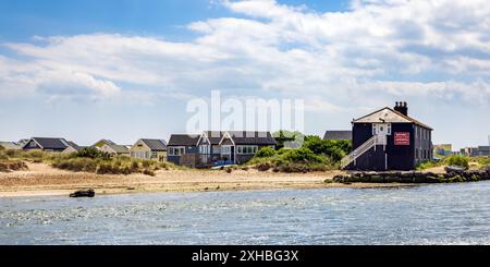 Das Black House und die Strandhütten auf der Mudeford Spit vom Mudeford Quay, Dorset, England. Die Strandhütten hier sind die teuersten in Großbritannien. Stockfoto