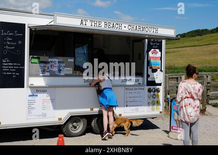 Touristen, die ein Eis in einem mobilen Imbiss am Charmouth Beach, Dorset, Großbritannien kaufen wollen - John Gollop Stockfoto