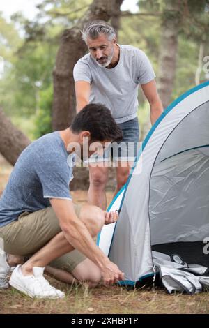 Junger Mann und älterer Freund, der ein Zelt aufbaut Stockfoto