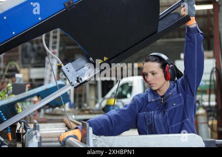 Weibliche Fabrikarbeiterin, die die Produktionslinie inspiziert Stockfoto