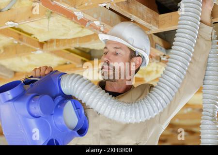 Männliche Fachfirma, die Lüftungssysteme in der Anlage installiert, die gerade renoviert wird Stockfoto