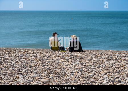 Ein Paar sitzt am Strand von Budleigh Salterton, Devon, Großbritannien Stockfoto