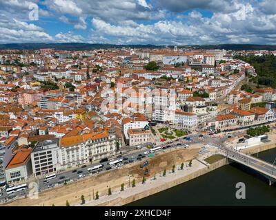 Weitwinkelaufnahme einer Stadt mit gekachelten Dächern und Fluss, umgeben von Hügeln und einem Himmel mit Wolken, aus der Luft, Coimbra, Rio Mondego, Portugal Stockfoto