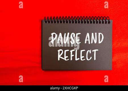 Unterbrechen und reflektieren Sie die Nachricht, die auf einer schwarzen Notizbuchseite mit rotem Hintergrund geschrieben wurde. Konzeptionelles Pause- und Reflexionssymbol. Kopierbereich. Stockfoto