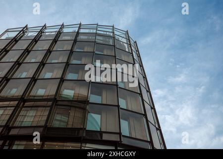Ein flaches Bild eines modernen Bürogebäudes mit einer eleganten Glasfassade vor dem Hintergrund eines klaren blauen Himmels. Stockfoto
