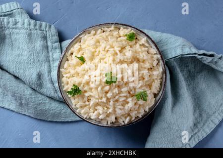 Weißer Reis, gekocht, mit Petersilie verziert, oben auf blauem Hintergrund geschossen Stockfoto