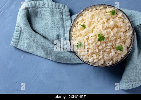 Reis in einer Schüssel, über Kopf auf einem blauen Hintergrund mit Copyspace geschossen Stockfoto