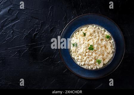 Reis mit Petersilie, von oben nach unten geschossen auf schwarzem Hintergrund. Einfache Beilage Stockfoto