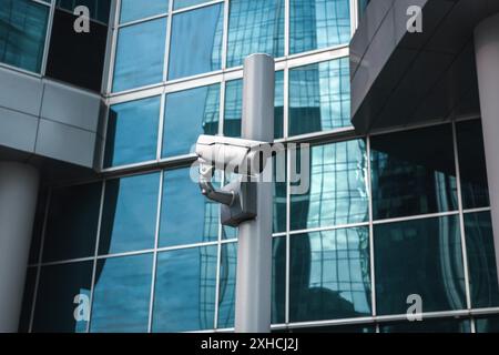 Externe Überwachungskamera gegen Glasfassade Stockfoto