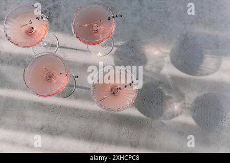 Gläser mit kaltem rosafarbenem Champagner und Lavendelblüten auf dem Tisch Stockfoto