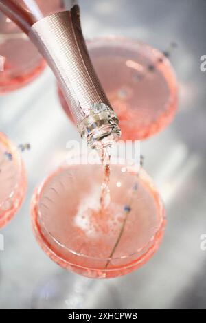 Gläser mit kaltem rosafarbenem Champagner und Lavendelblüten auf dem Tisch Stockfoto