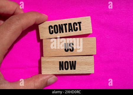 Kontaktieren Sie uns jetzt Wörter auf Holzblöcken mit rosa Hintergrund. Konzeptionelles Kontaktieren Sie uns jetzt Symbol. Kopierbereich. Stockfoto