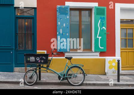 Das Fahrrad parkt vor den farbenfrohen Häusern in der Rue Sainte-Marthe, einer kleinen Straße im 10. Arrondissement von Paris, Frankreich. Stockfoto