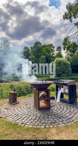 Barbecue auf der Steinterrasse bei Sonnenuntergang im hellen Garten. Vertikales Foto Stockfoto