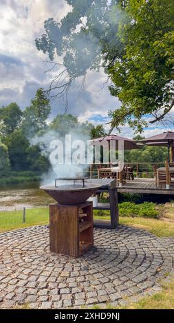 Barbecue auf der Steinterrasse bei Sonnenuntergang im hellen Garten. Vertikales Foto Stockfoto