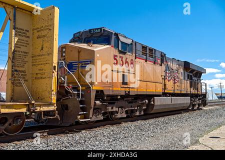 Die Union Pacific Lokomotive 5368 versorgt einen Zug, der durch das alte Depot in Nyssa, Oregon, USA fährt Stockfoto