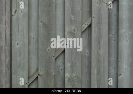 Nahaufnahme eines grauen, verwitterten, druckbehandelten Holzzauns. Stockfoto