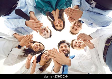 Bild von unten: Fröhliche Geschäftsleute, die in die Kamera hinunterschauen und applaudieren. Stockfoto