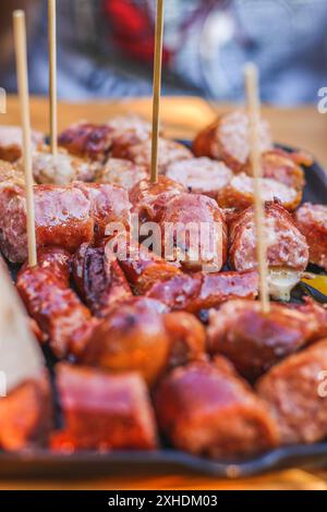 Aus nächster Nähe gegrillte Würstchen auf Holzspießen in einer Pfanne, einige mit einem leichten Saibling. Stockfoto