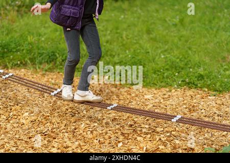 Die Beine der Kinder balancieren an einem Seil. Kinderfüße in Schuhen Nahaufnahme. Das Konzept der glücklichen Kindheit Stockfoto