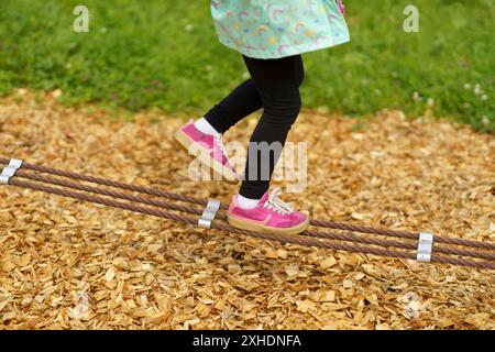 Die Beine der Kinder balancieren an einem Seil. Kinderfüße in Schuhen Nahaufnahme. Das Konzept der glücklichen Kindheit Stockfoto