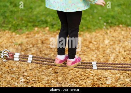 Die Beine der Kinder balancieren an einem Seil. Kinderfüße in Schuhen Nahaufnahme. Das Konzept der glücklichen Kindheit Stockfoto