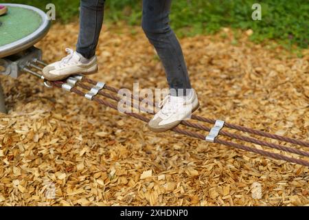 Die Beine der Kinder balancieren an einem Seil. Kinderfüße in Schuhen Nahaufnahme. Das Konzept der glücklichen Kindheit Stockfoto