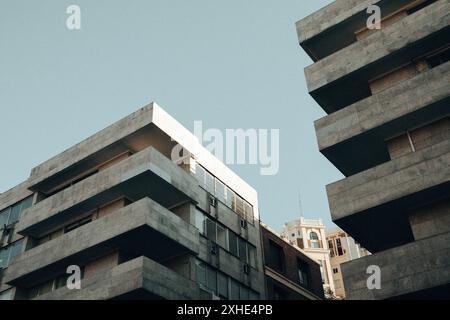 Außenansicht des symmetrischen, grauen Gebäudes aus Beton mit langen Balkonen und flachem Blickwinkel. Moderne Architektur im Stil des Brutalismus. Stadtwohnung Stadthäuser. Stockfoto