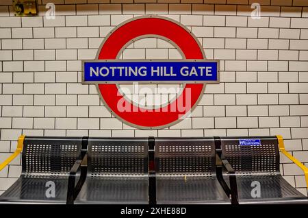 Ein Londoner U-Bahn-Symbol an der Wand der Notting Hill Gate Station über einer Reihe von Sitzplätzen. Stockfoto