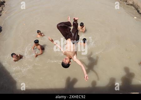 Balkh. Juli 2024. Dieses Foto vom 13. Juli 2024 zeigt afghanische Jungen, die im Wasser spielen, um sich in Mazar-i-Sharif, der Hauptstadt der Provinz Balkh im Norden Afghanistans, abzukühlen. Quelle: M Fardin Nawrozi/Xinhua/Alamy Live News Stockfoto