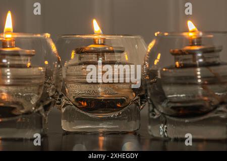 Drei Glaskerzen auf Holztisch mit warmer Hintergrundgruppe Stockfoto