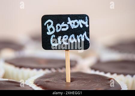 Schwarzes Holzschild mit der Aufschrift Boston Cream in Boston Cream Cupcake an der Dessert Bar Stockfoto