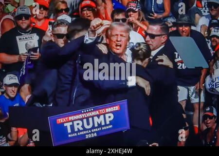 In dieser Fotoabbildung zeigt ein Bildschirm den ehemaligen US-Präsidenten Donald Trump, der bei einer Kundgebung in Butler ins Ohr geschossen hat. Der ehemalige US-Präsident Donald Trump wurde bei einer Schießerei bei einer Kundgebung, die er im Rahmen seiner Wahlkampagne vor den US-Präsidentschaftswahlen 2024 in Butler, Pennsylvania, abgehalten hatte, verwundet. Laut den neuesten Berichten töteten Geheimagenten einen Schützen und ein Teilnehmer der Kundgebung starb durch den Schützen selbst. Die Schießerei bei der Kundgebung wird als versuchter Mord an dem ehemaligen Präsidenten Trump untersucht, berichtet Associated Press unter Berufung auf den Butler Stockfoto