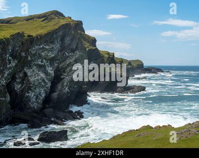 Seevögelklippen bedeckt mit Guano von nistenden Seevögeln mit Wellen und Surfen unten in Pig's Paradise, June, Isle of Colonsay, Schottland, Großbritannien Stockfoto