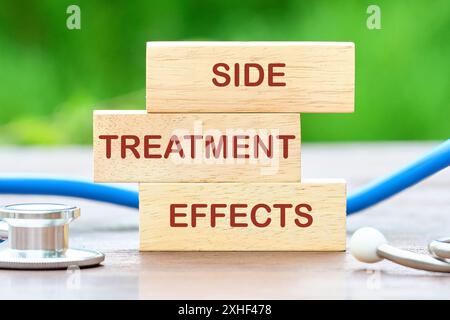 Begriffliches Nebenwirkungen-Symbol. Kopierbereich. NEBENBEHANDLUNGSWIRKUNGEN Wörter auf Holzblöcken vor dem Hintergrund von verschwommenen grünen Pflanzen Stockfoto