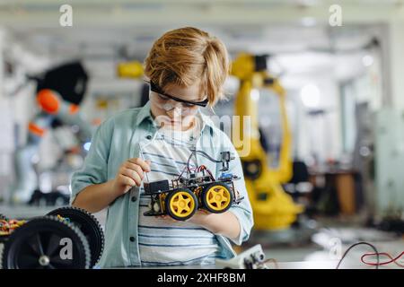 Porträt eines Schülers, der ein Roboterauto im Robotikclub der Schule baut. Kinder, die Robotik in der Grundschule lernen. Wissenschaft für Kinder. Stockfoto