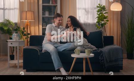 Multirassisch positives glückliches Paar Familie Kaukasischer Mann Mann männlich Hispanic Latino Frau Mädchen weiblich Lächeln sprechen mit Handy zusammen Stockfoto