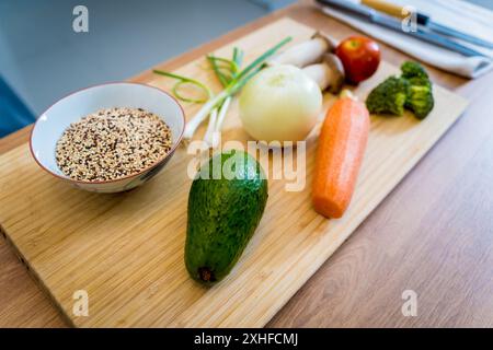 Schneidebrett mit Zutaten für die Zubereitung gesunder Quinoa-Schüssel mit Avocado Stockfoto