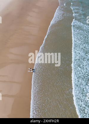 2 Surfer stehen am Sandstrand in der Nähe der Wellen aus der Vogelperspektive Stockfoto