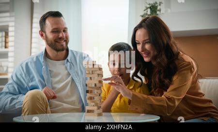 Glückliche Liebe verspielte kaukasische Familie Mutter Vater Mutter Vater Vater Eltern geliebter Sohn Kind Kind Kind spielen intellektuell logische Brettspiel zusammen in Cozy Stockfoto