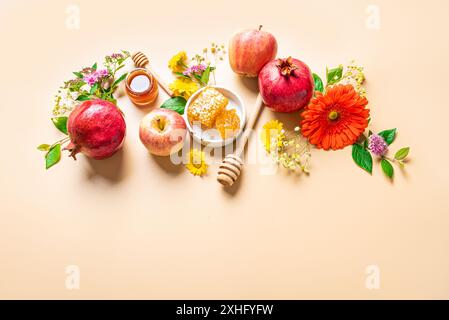 Rosh Hashanah jüdisches Neujahrskonzept. Kreatives Design traditioneller Symbole - Äpfel, Honig, Granatapfel und Blumen auf orange-beige Backgro Stockfoto