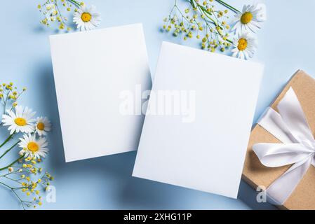 Gruß- oder Einladungskarten-Mockup, zwei weiße leere Blanks mit Blumendekor auf Bue-Hintergrund, Kopierraum. Stilvolles, kreatives Modell mit weißem Chamom Stockfoto