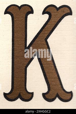 Ein dekorativer, antiker Großbuchstabe K in Gold mit schwarzer Umrandung auf cremefarbenem Hintergrund. Stockfoto